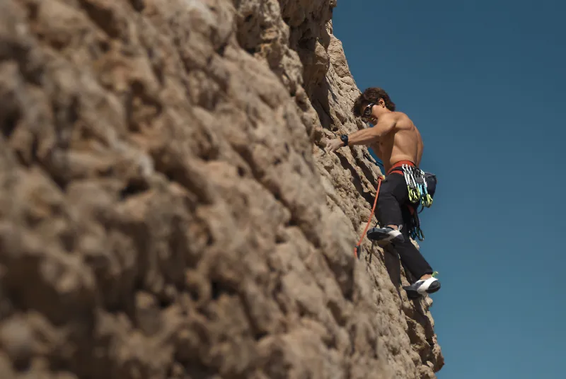 A man wearing a Garmin watch climbs outside